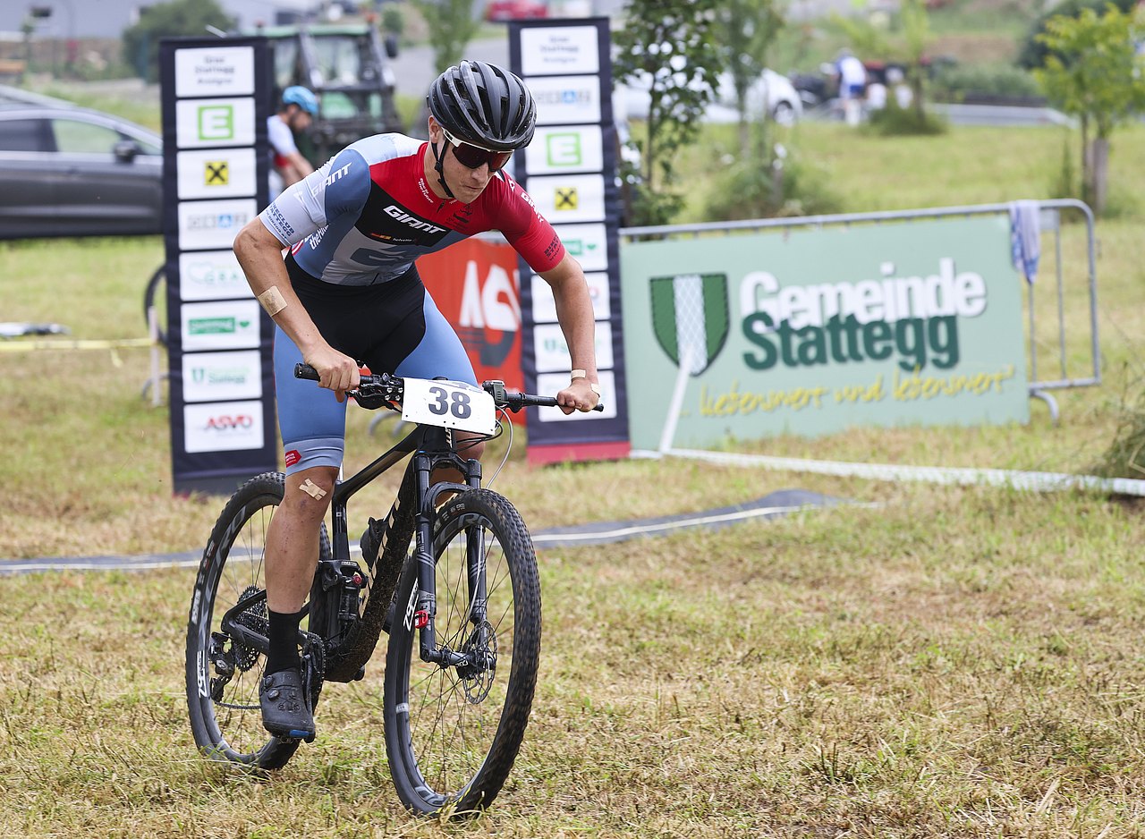 Franz-Josef Lässer fährt auf seinem Mountainbike auf einer Grasfläche. Vier Finger fehlen ihm an der linken Hand. 