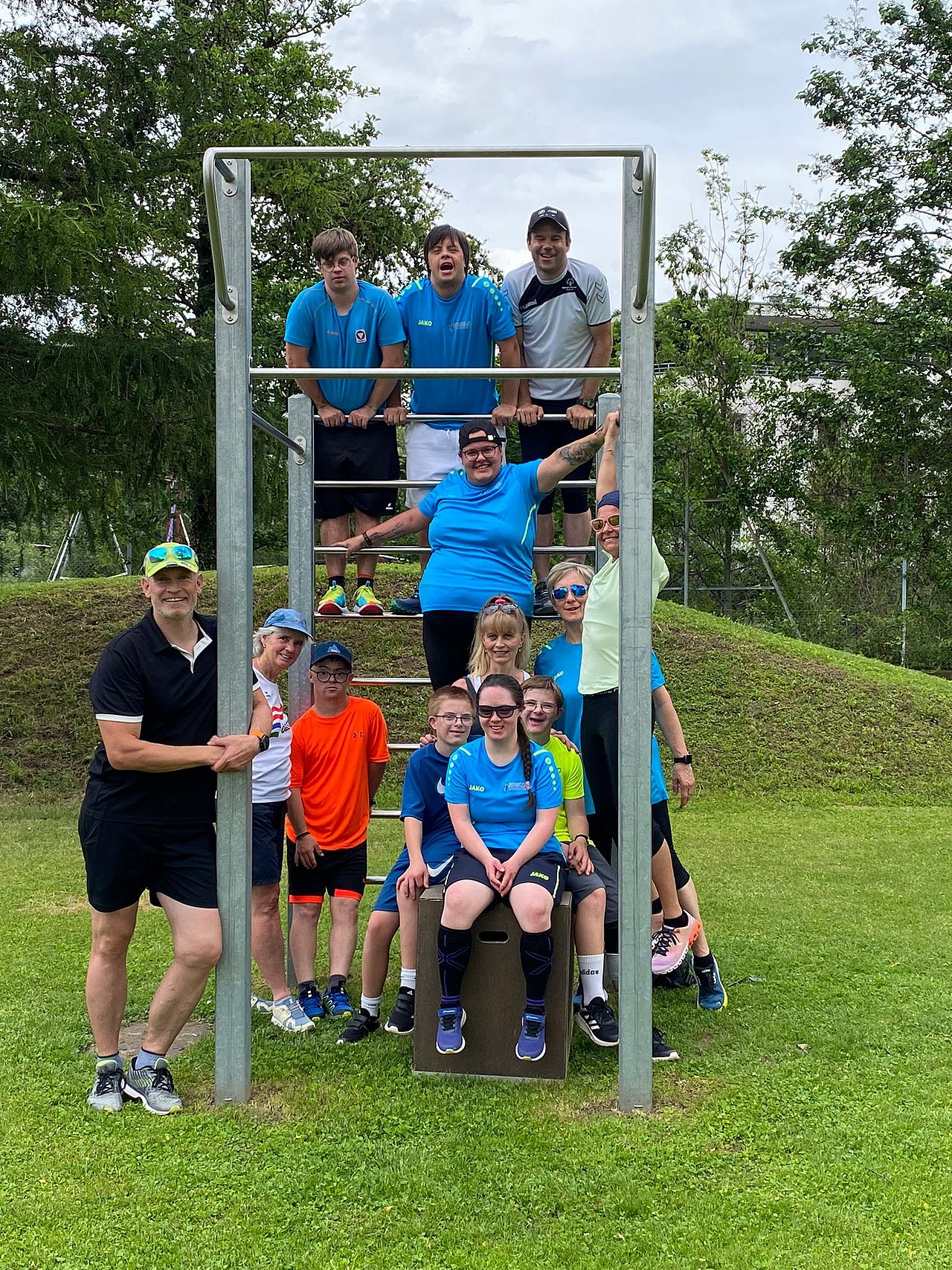 [Translate to Deutsch (Leichte Sprache):] Die Sportlerinnen und Sportler haben sich für das Gruppenfoto auf einem Klettergerüst positioniert und schauen in die Kamera.