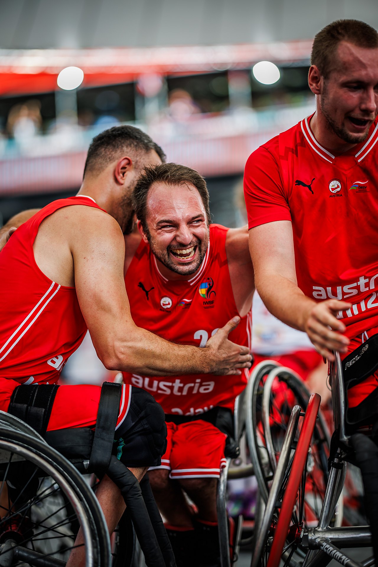 Die Rollstuhl-Basketballer Österreichs in roten Shirts umarmen sich lachend nach dem entscheidenden Wurf.