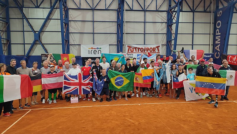 Auf dem Tennisplatz stehen zahlreiche Tennis-Spielerinnen mit Amputationen. Sie halten die Flagge ihres Herkunftslandes in die Kamera.