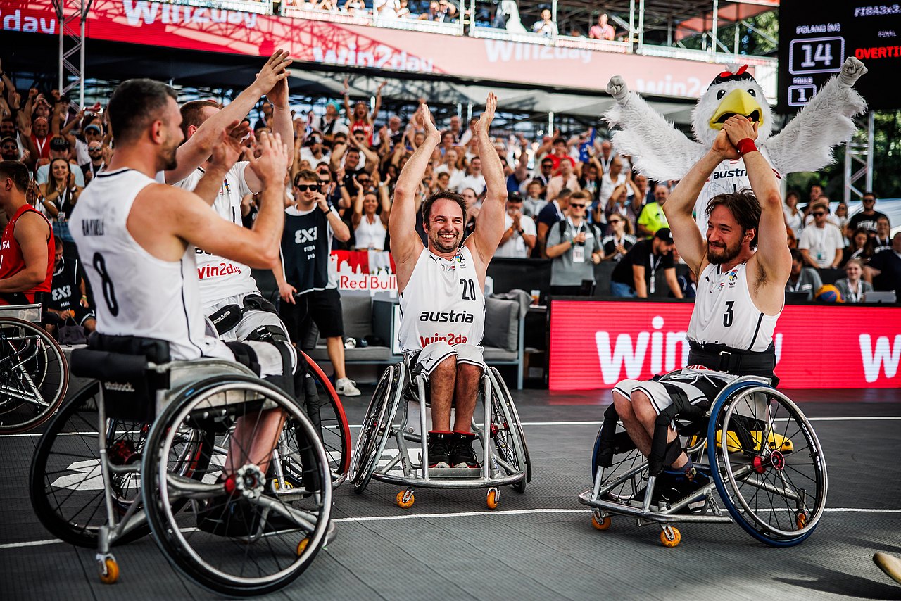 Die österreichischen Rollstuhl-Basketballer feiern auf dem Platz vor einem stehenden Publikum.